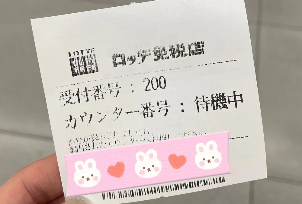手に持った受付番号の紙、200番の表示